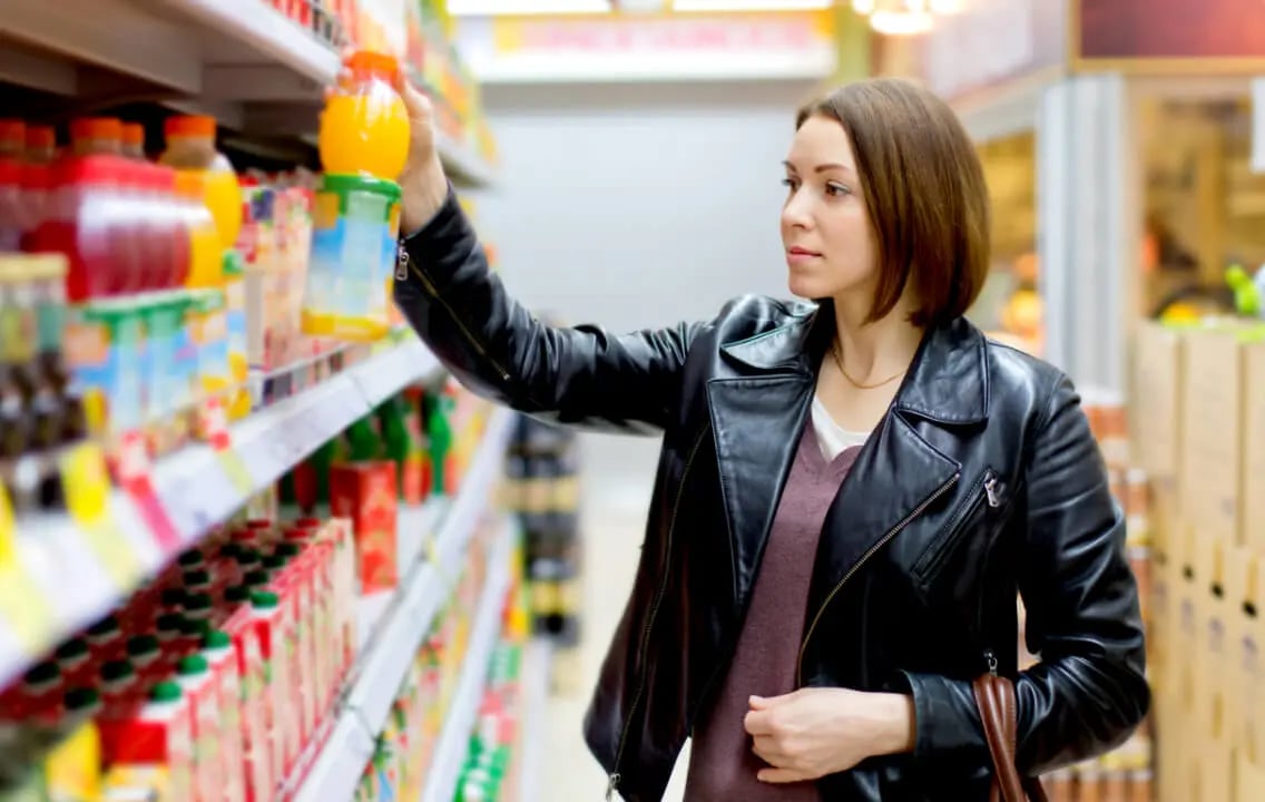 A woman surveys a shelf of beverages, illustrating a focus on trade strategy to drive financial efficiencies